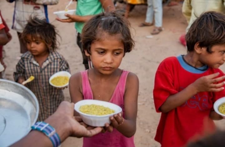 Children receiving bowls of prepared food during a community meal distribution